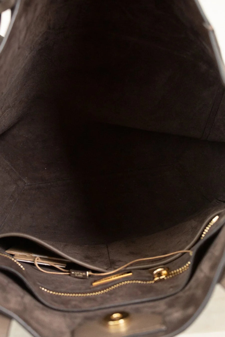 Close-up of a brown leather bag with gold zipper and hardware.