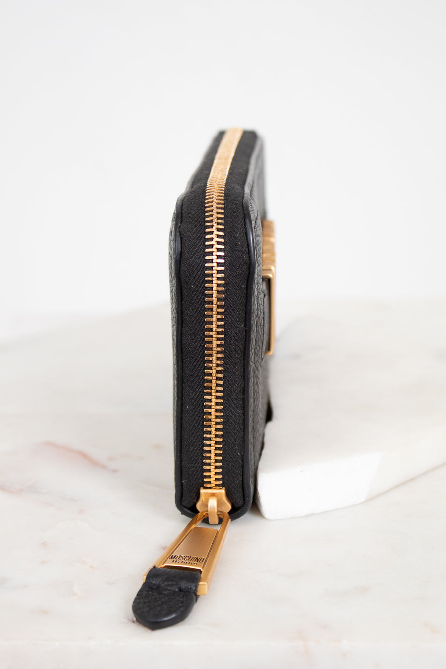 Black wallet with gold zipper on a white background