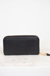 Black wallet with gold zipper on a white marble surface