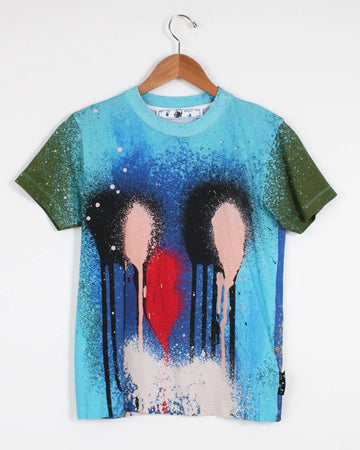 T-shirt with artistic design of three abstract figures and a red heart on a hanger against a white background