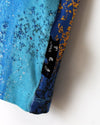 Close-up of a blue and gold patterned fabric with a visible brand label.