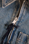 Close-up of a blue denim jacket zipper with brand label
