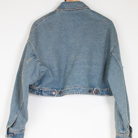 Blue denim jacket on a hanger against a white background