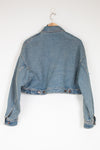 Blue denim jacket on a hanger against a white background