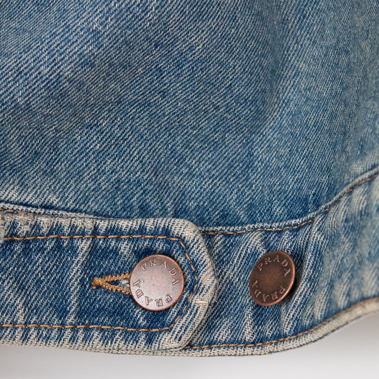 Close-up of a blue denim jacket with two buttons on a white background