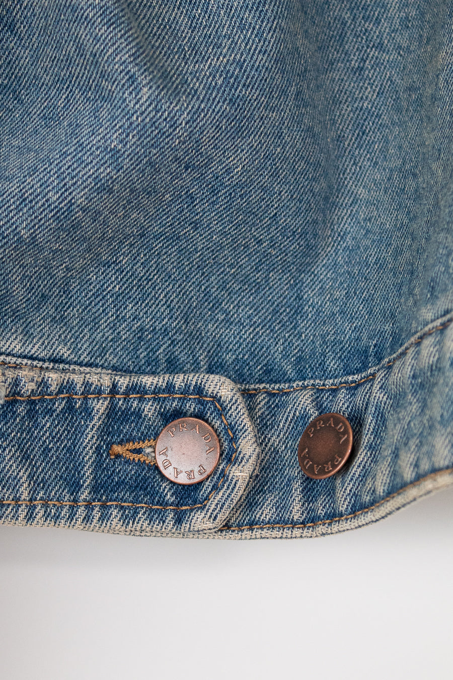 Close-up of a blue denim jacket with two buttons on a white background