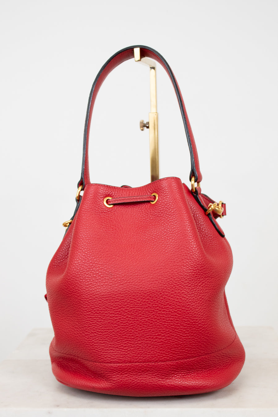 Red leather handbag with gold accents on a light gray background