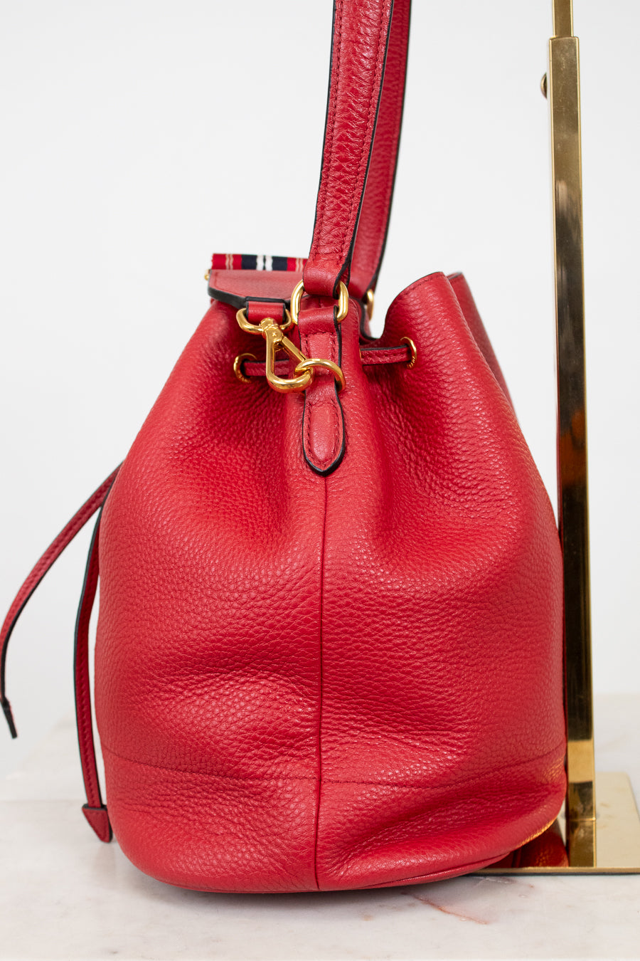 Red leather bucket bag with gold clasp on a white background