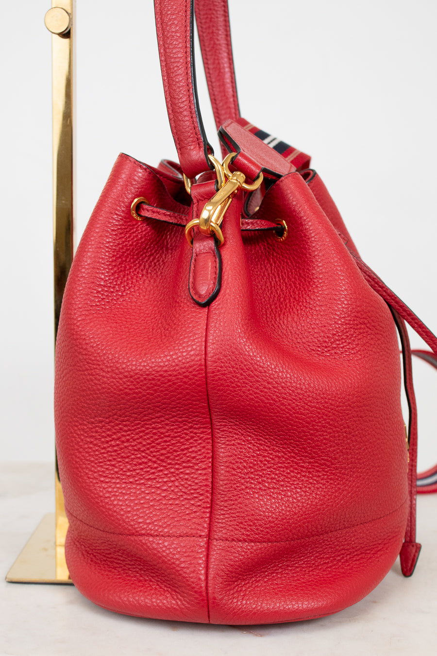 Red leather bucket bag with gold clasp on a white background