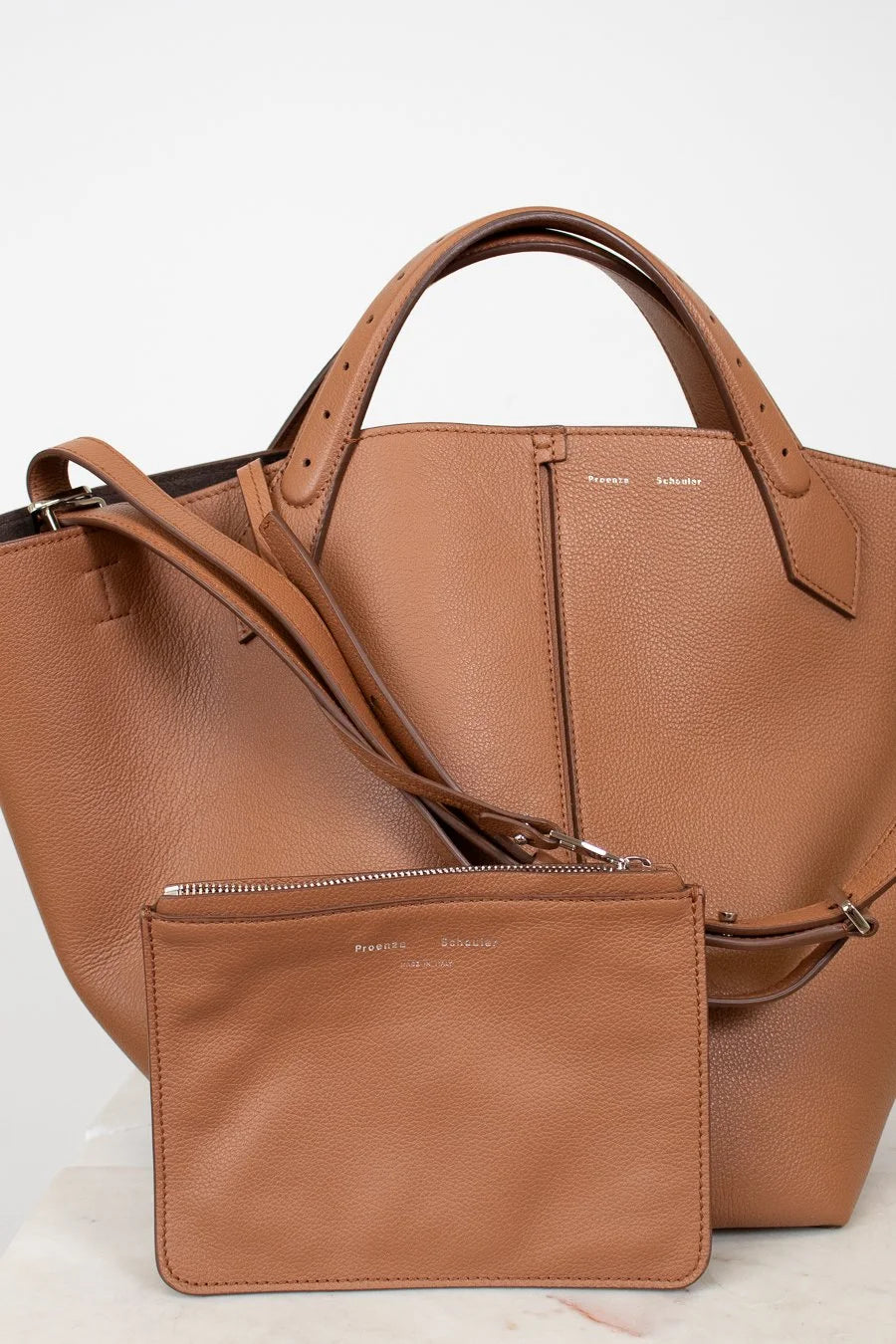 Brown leather handbag with matching pouch on a white background