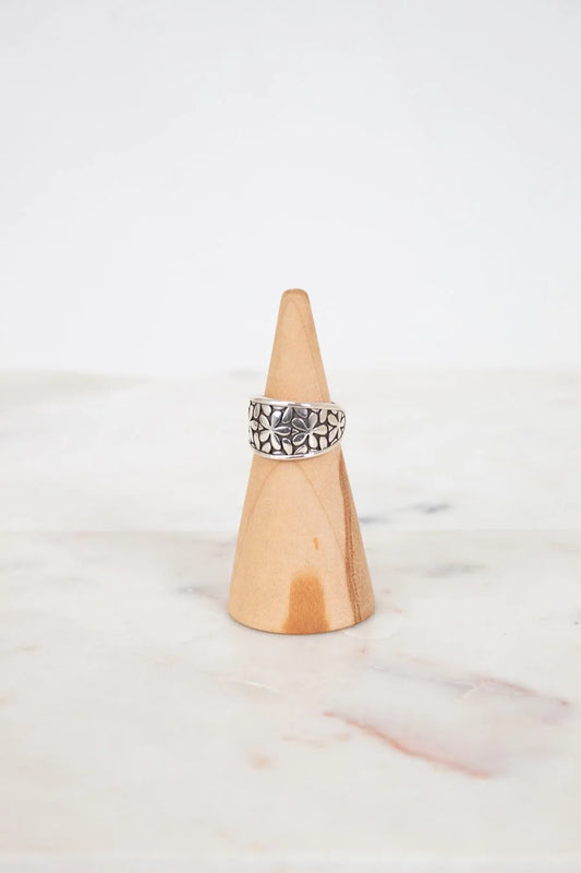 Silver ring on a wooden cone against a white background
