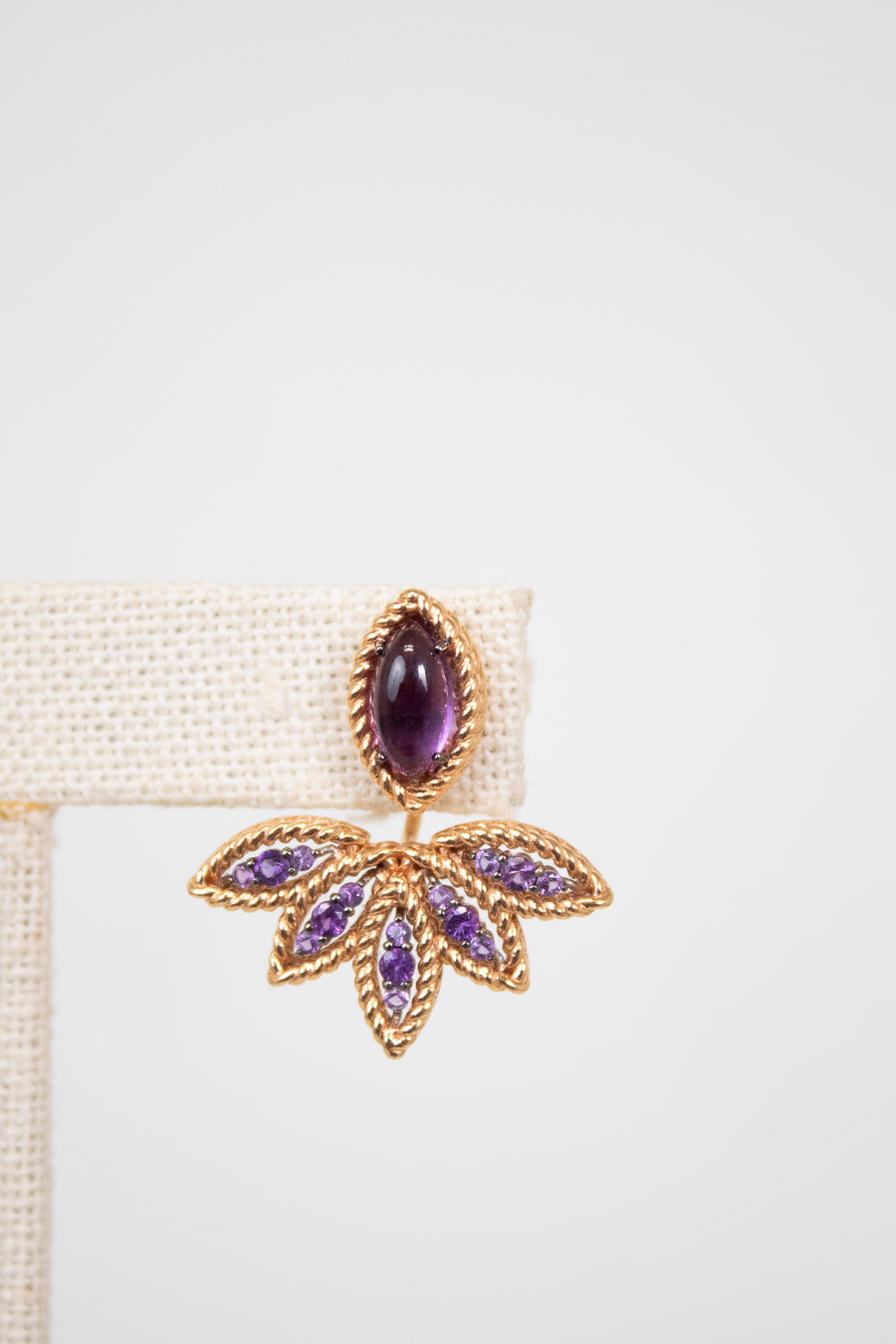 Leaf shaped gold and purple earring on white background