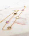 Gold necklace with purple and brown stones on a marble surface