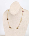 Gold necklace with purple stones on a mannequin bust against a white background