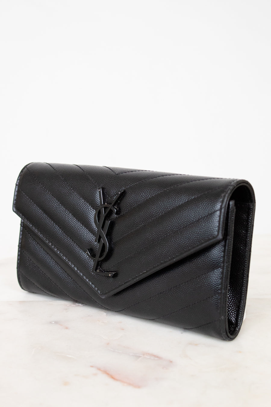 Black quilted wallet bag on a light marble surface