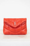 Red quilted handbag with a brand logo on a light beige background