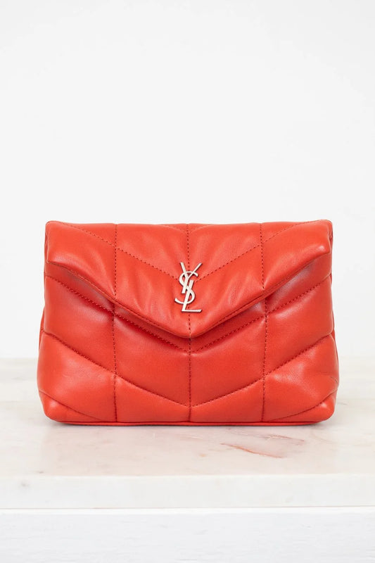 Red quilted handbag with a brand logo on a light beige background
