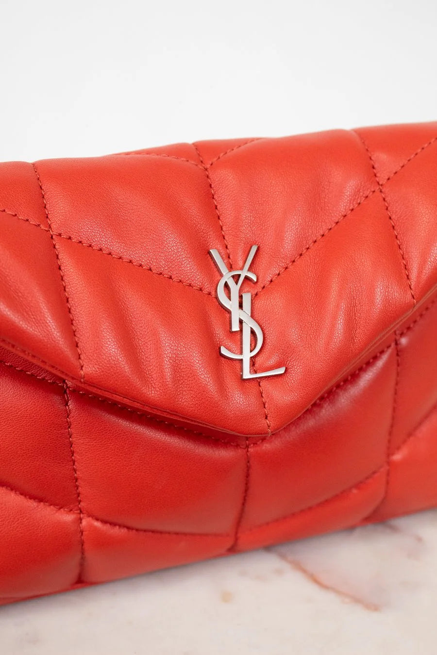 Red quilted handbag with a brand logo on a light background