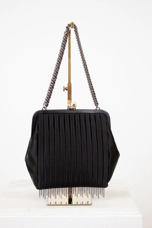 Black handbag with chain strap and fringe details on a white background
