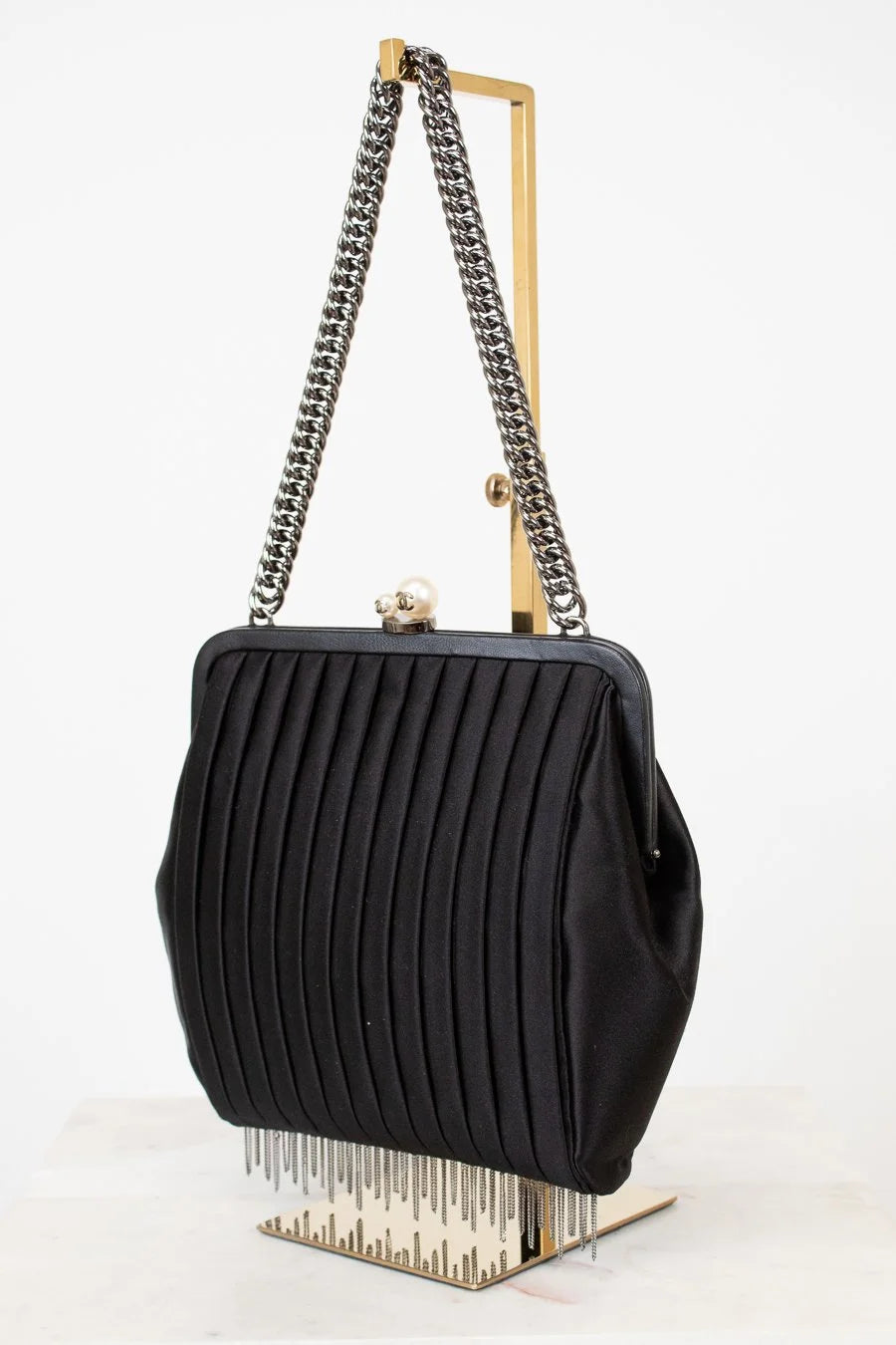 Black pleated handbag with chain strap on a white background