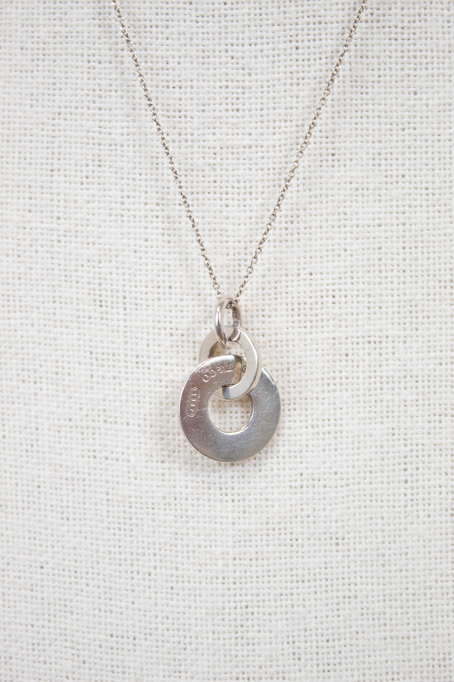 Silver necklace with a unique pendant on a light gray background