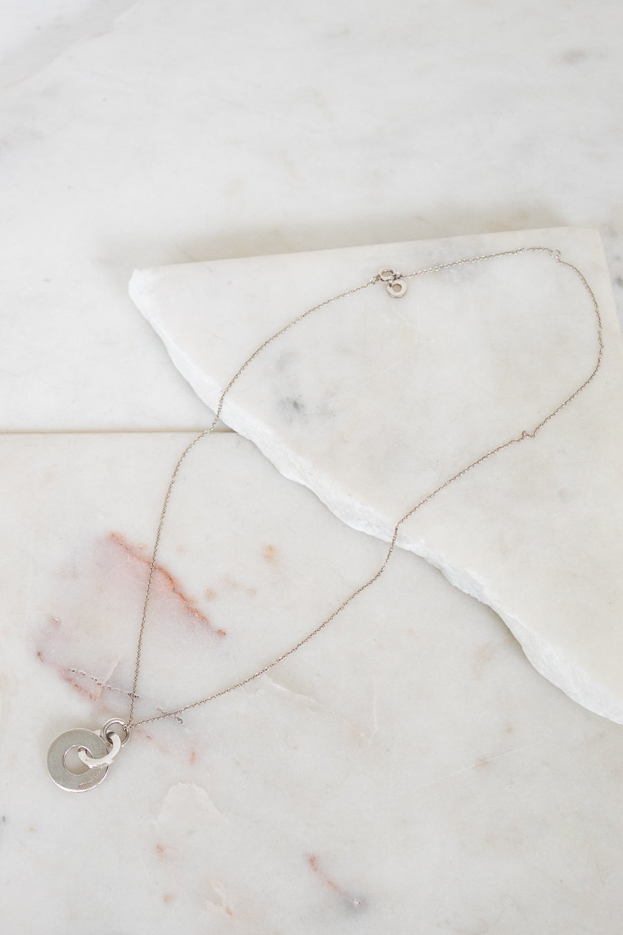 Necklace with a interlocking circles pendant on a marble surface