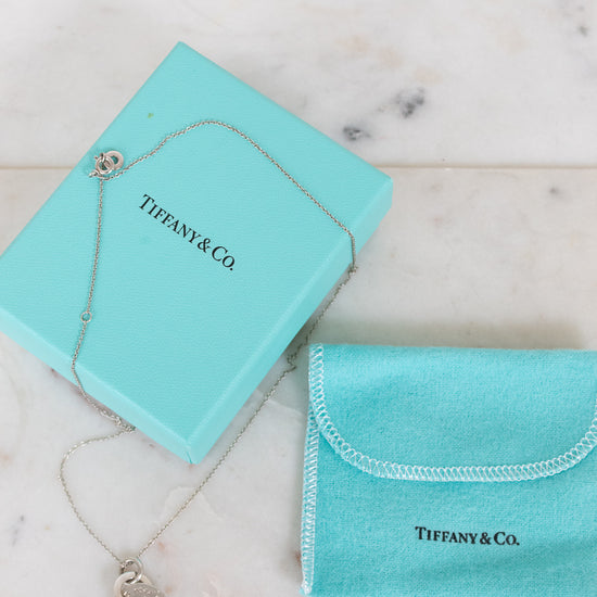 Tiffany & Co. jewelry box with necklace and pouch on a marble surface