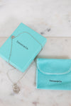 Tiffany & Co. jewelry box with necklace and pouch on a marble surface