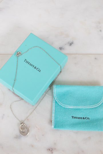 Tiffany & Co. jewelry box with necklace and pouch on a marble surface