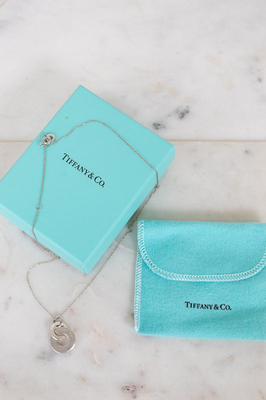 Tiffany & Co. jewelry box with necklace and pouch on a marble surface
