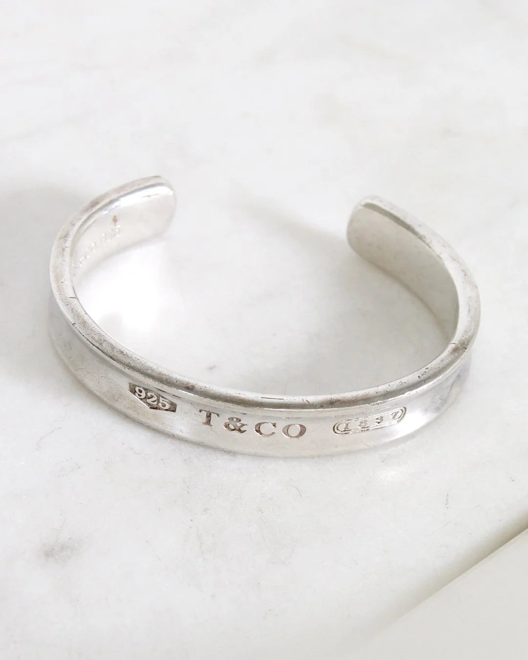Silver bracelet with 'T&CO' engraving on a marble surface