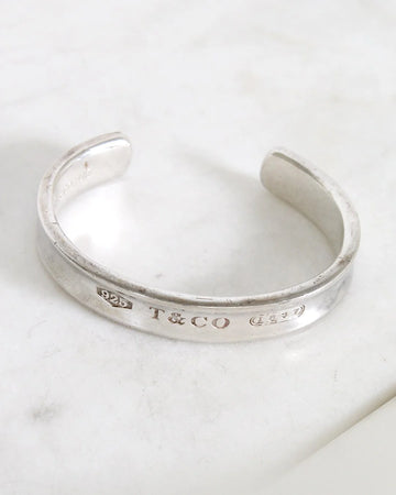 Silver bracelet with 'T&CO' engraving on a marble surface