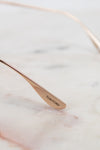 Rose gold spoon with 'Tom Ford' engraving on a marble surface
