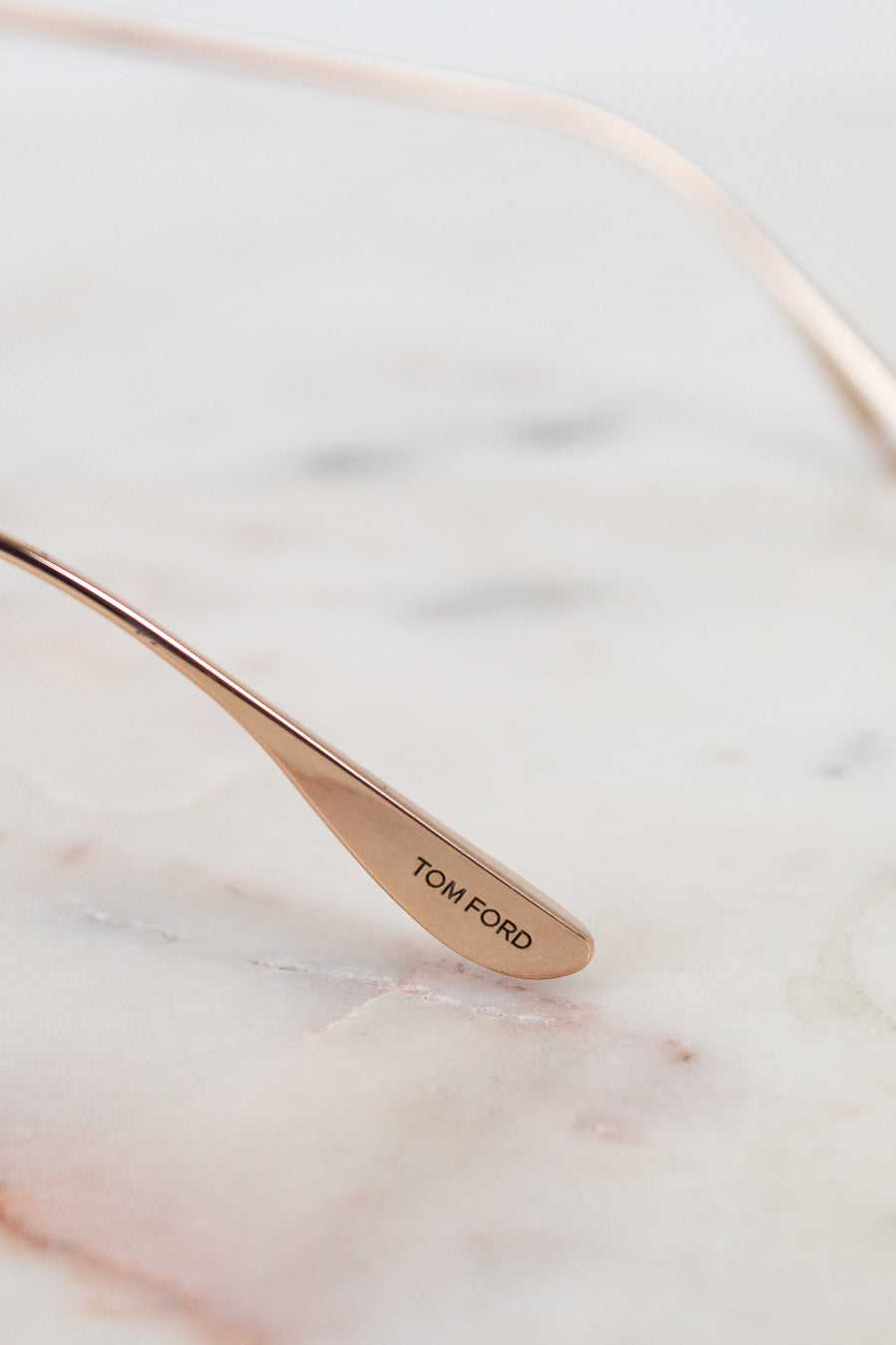 Rose gold spoon with 'Tom Ford' engraving on a marble surface