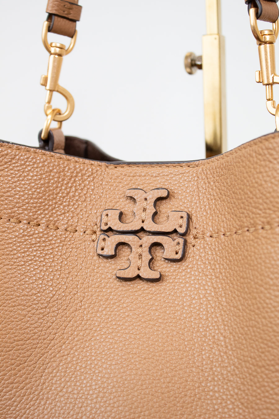Close-up of a brown leather handbag with gold hardware and a visible brand logo.
