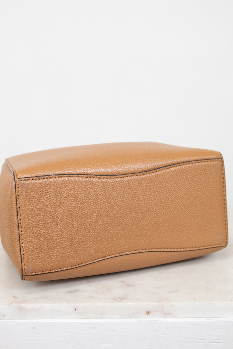 Tan leather handbag on a light marble surface