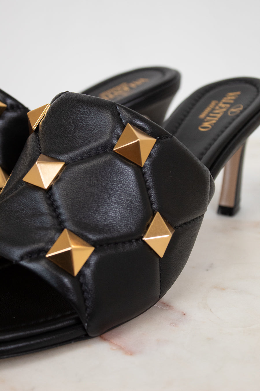 Black high-heeled shoes with gold studs on a light background