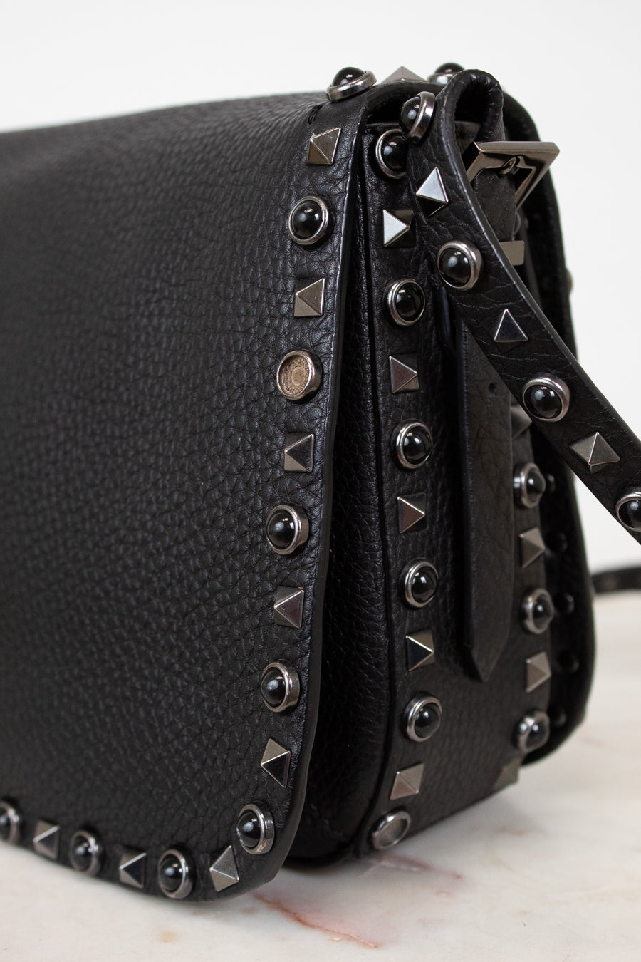 Black leather handbag with studded details on a white background