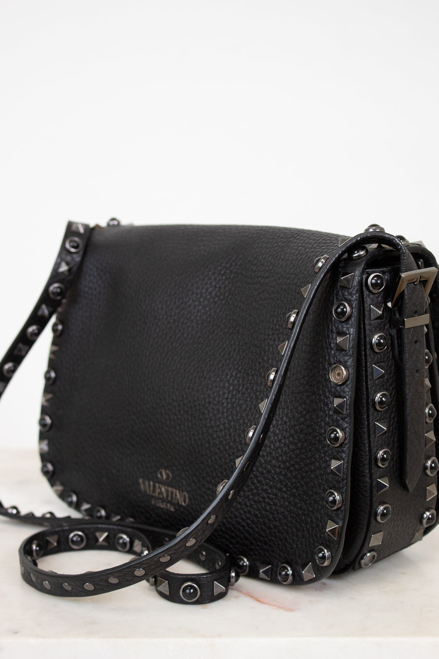 Black leather handbag with studded details on a white background