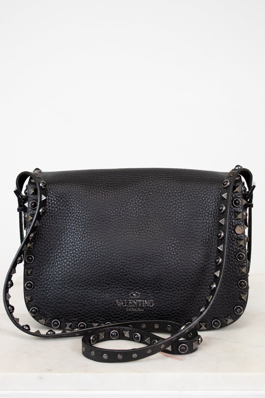 Black leather handbag with studs on a white background