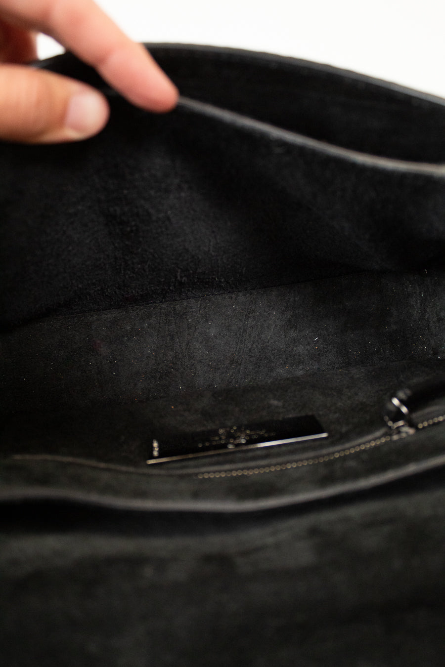 Close-up of a black handbag with a hand opening it