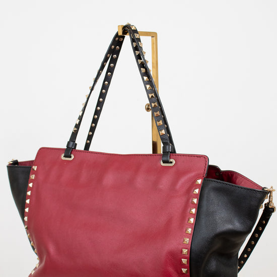 Red and black handbag with studded details on a white background