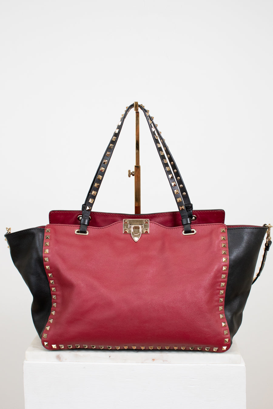Red and black handbag with studded details on a white background