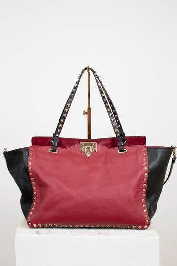 Red and black handbag with studded details on a white background
