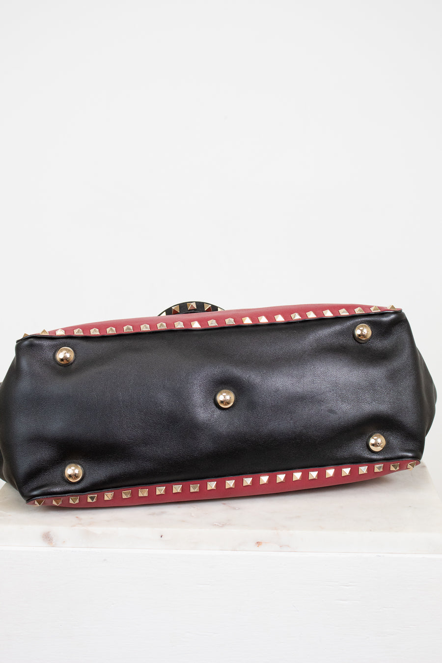 Black handbag with gold studs on a white background