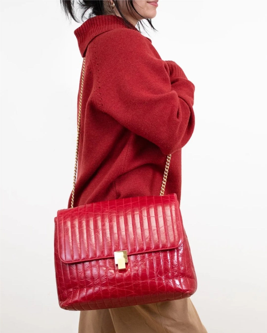 Person wearing a red crocodile-patterned handbag on a white background