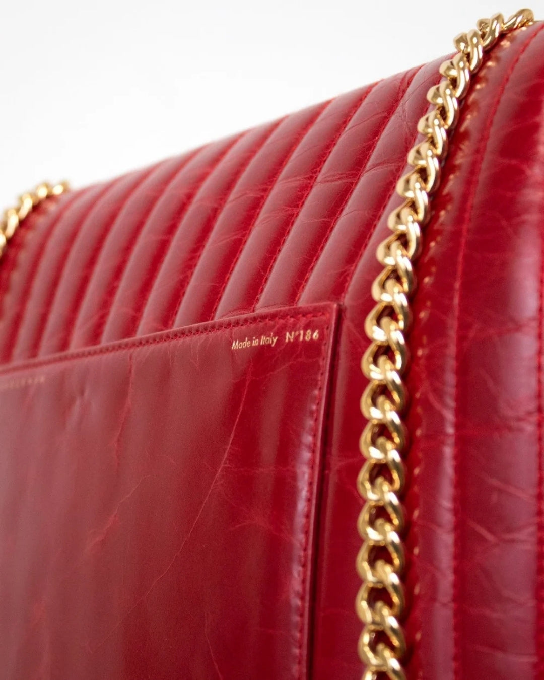 Red handbag with gold chain strap on a white background