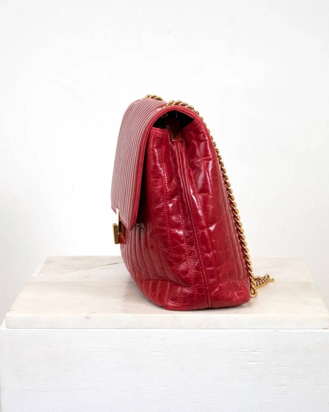 Red textured handbag with gold chain on a white background