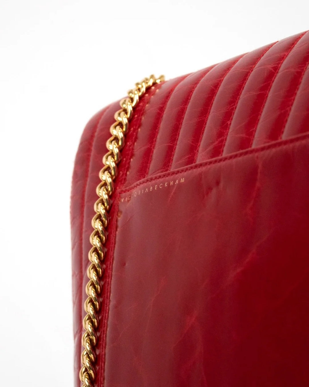 Close-up of a red handbag with gold chain detail on a white background