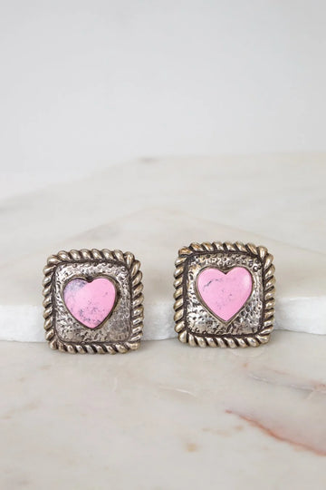 Pair of earrings with pink heart design on a marble surface